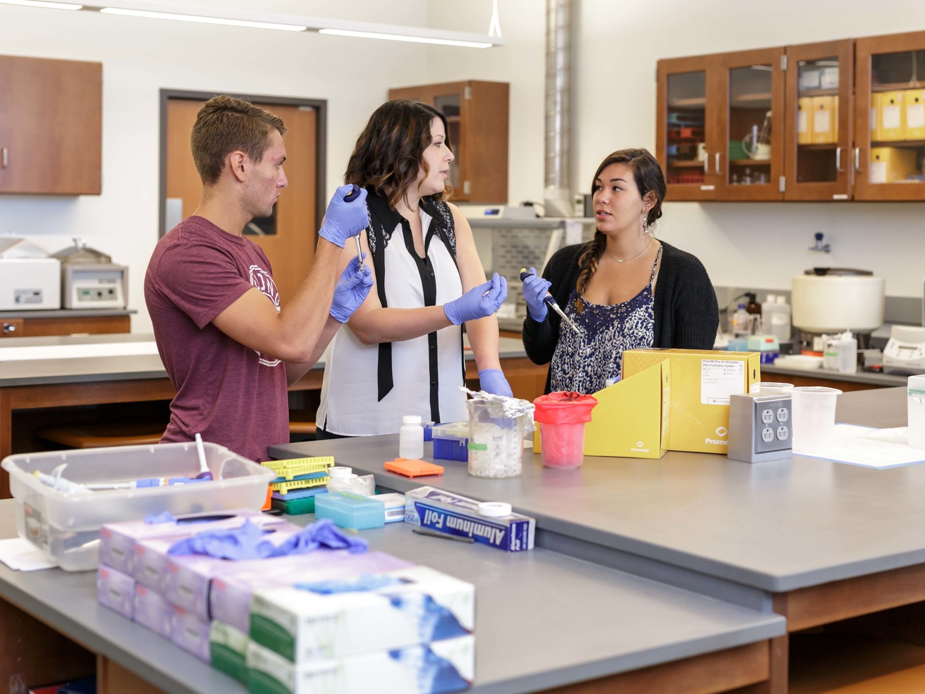 Two students and their professor work in a lab