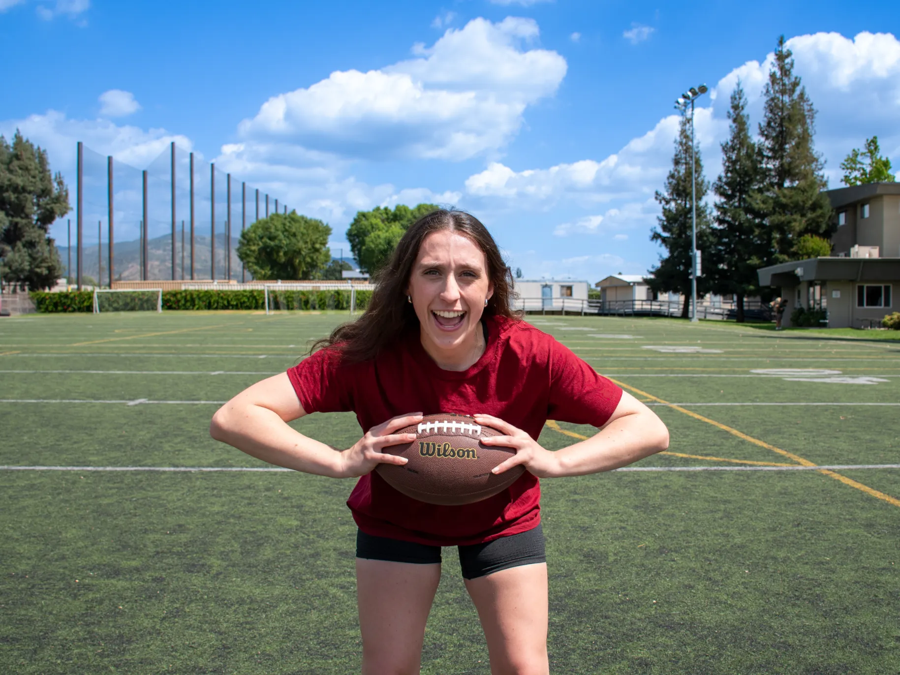A female student athlete poses with a football.