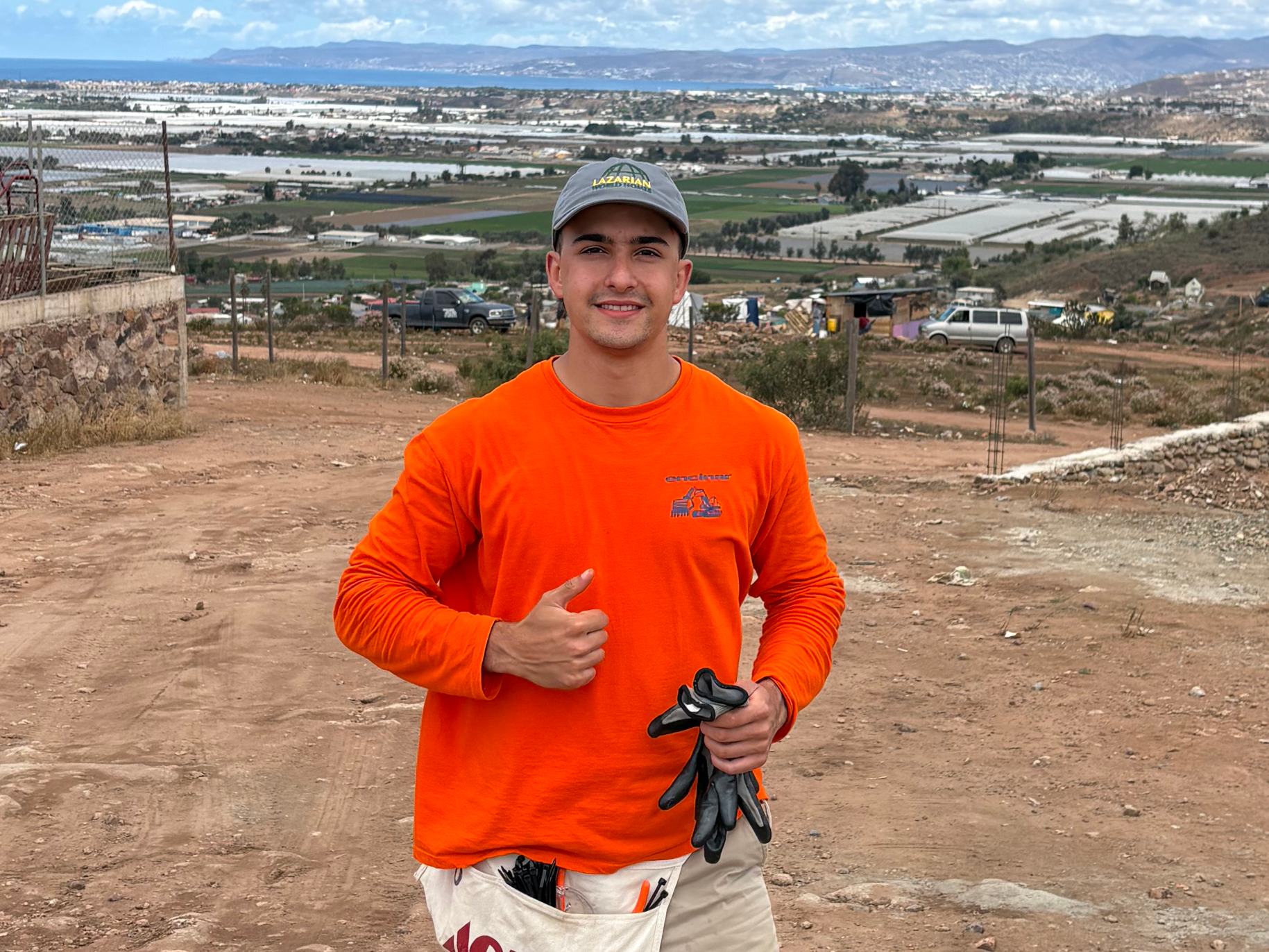Beltran gives a thumbs up at the building site with his gloves and tools.