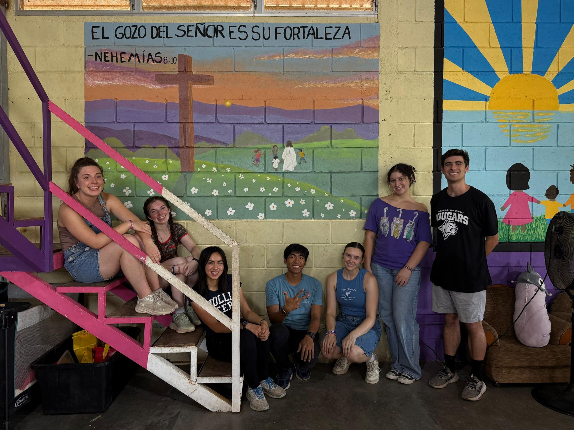 Olivia and the Honduras GE team smile in front of colorful murals.