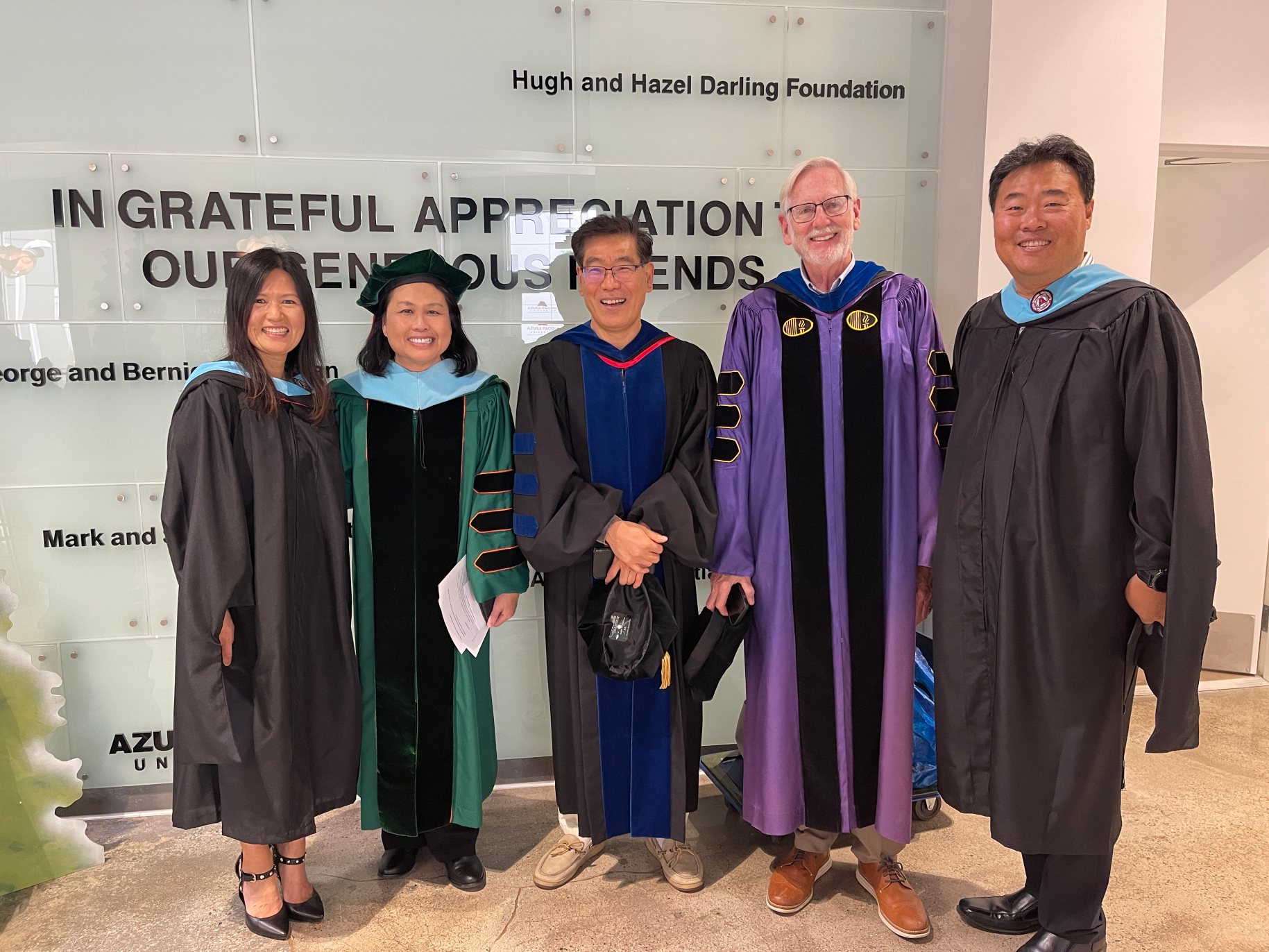 Charles and Sunny Cho standing with faculty members at graduation.