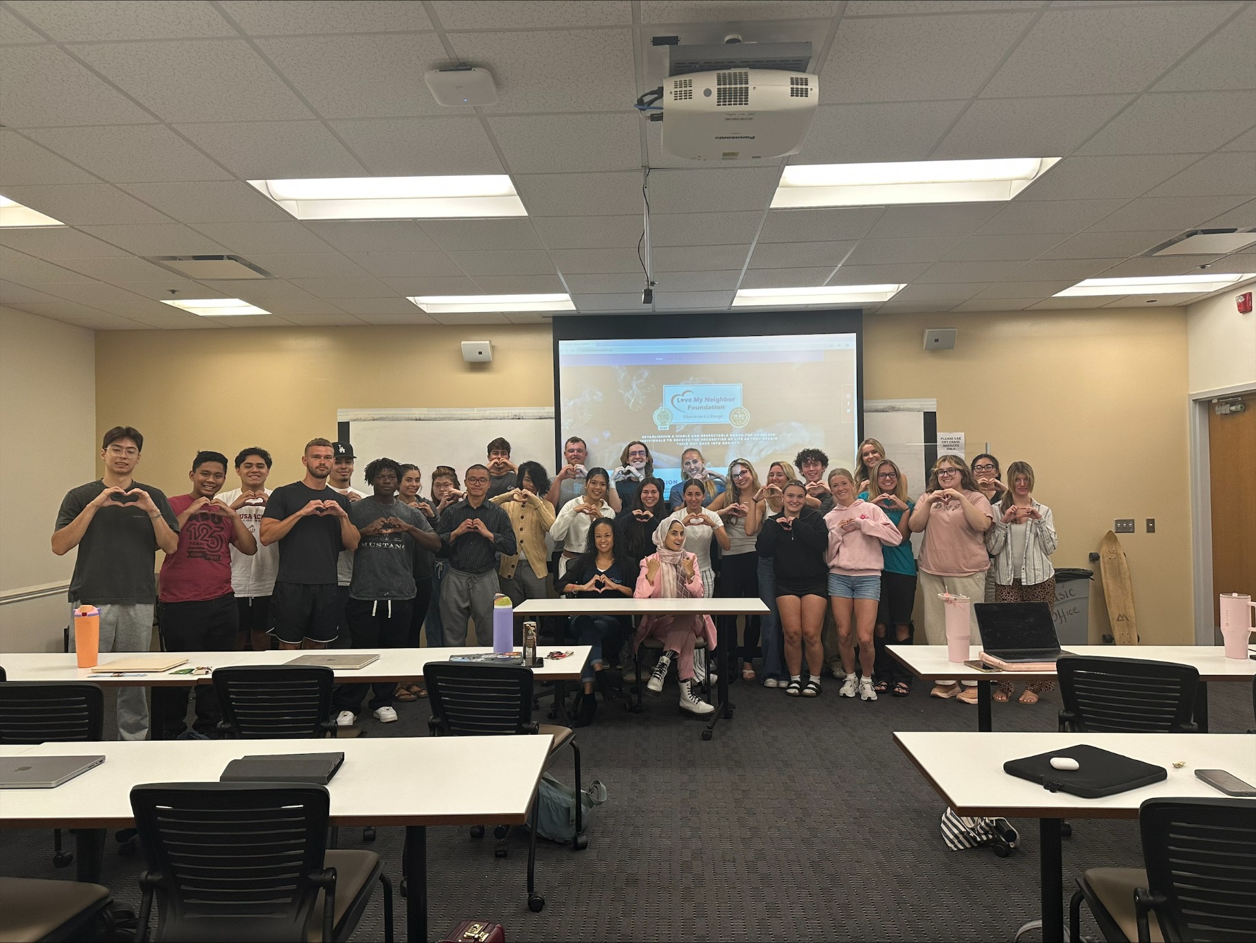 Large group of students stand by presentation, smiling.