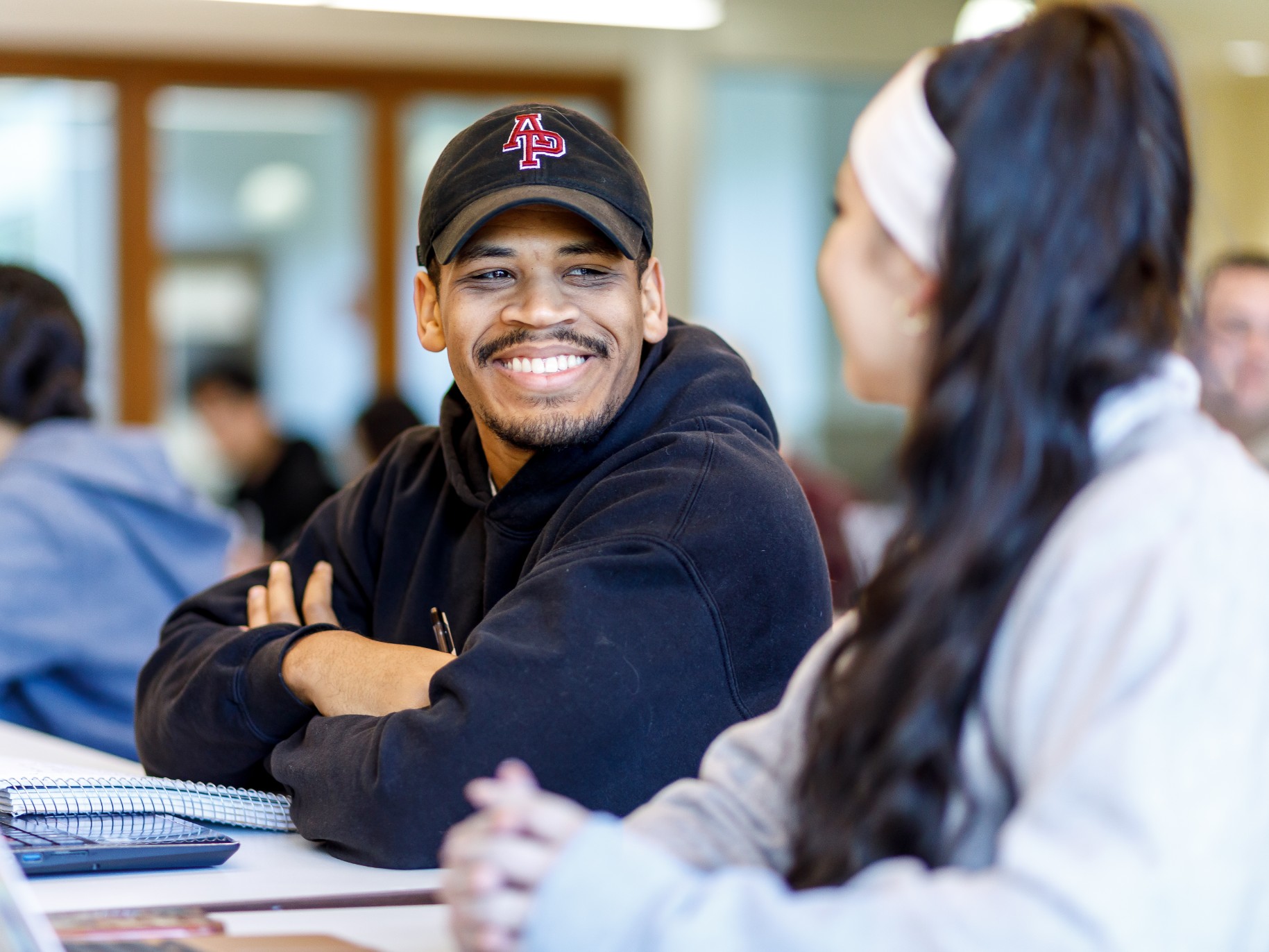 Two students smile at each other in a classroom