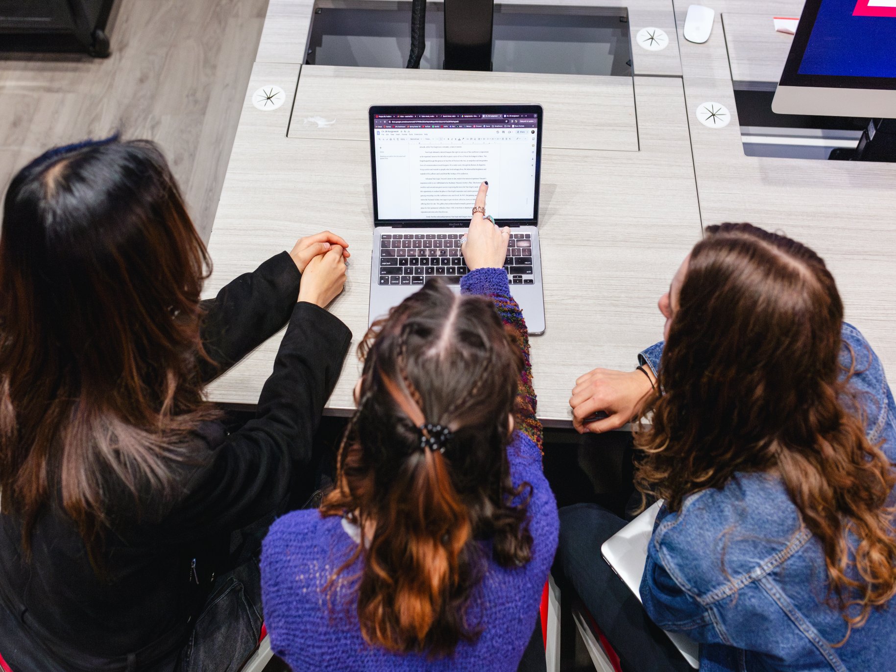 Three students looking at a laptop screen