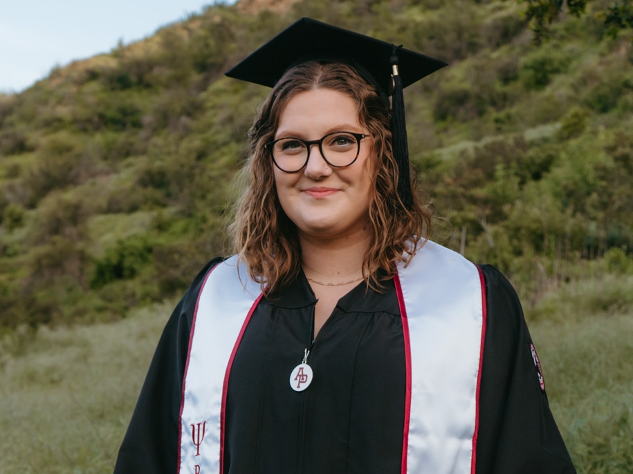 Hannah Frey outside in her APU graduation cap and gown.