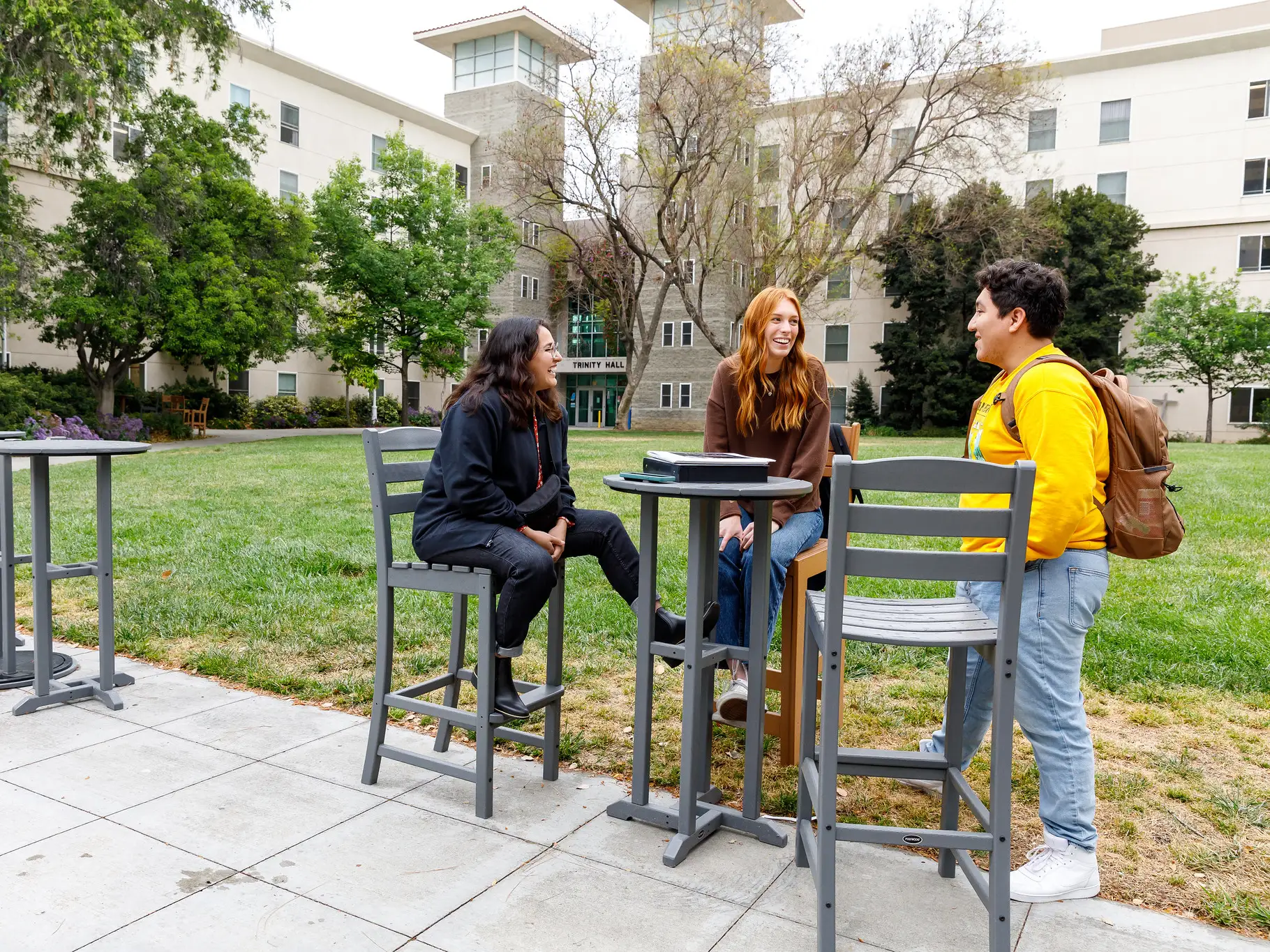 Three students talk in front of Trinity Hall