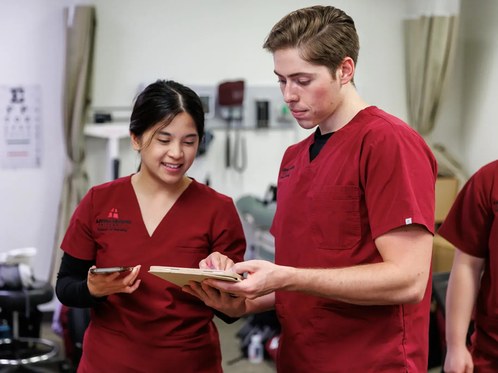 Azusa Pacific University nursing students review clinical information together in a simulation lab.