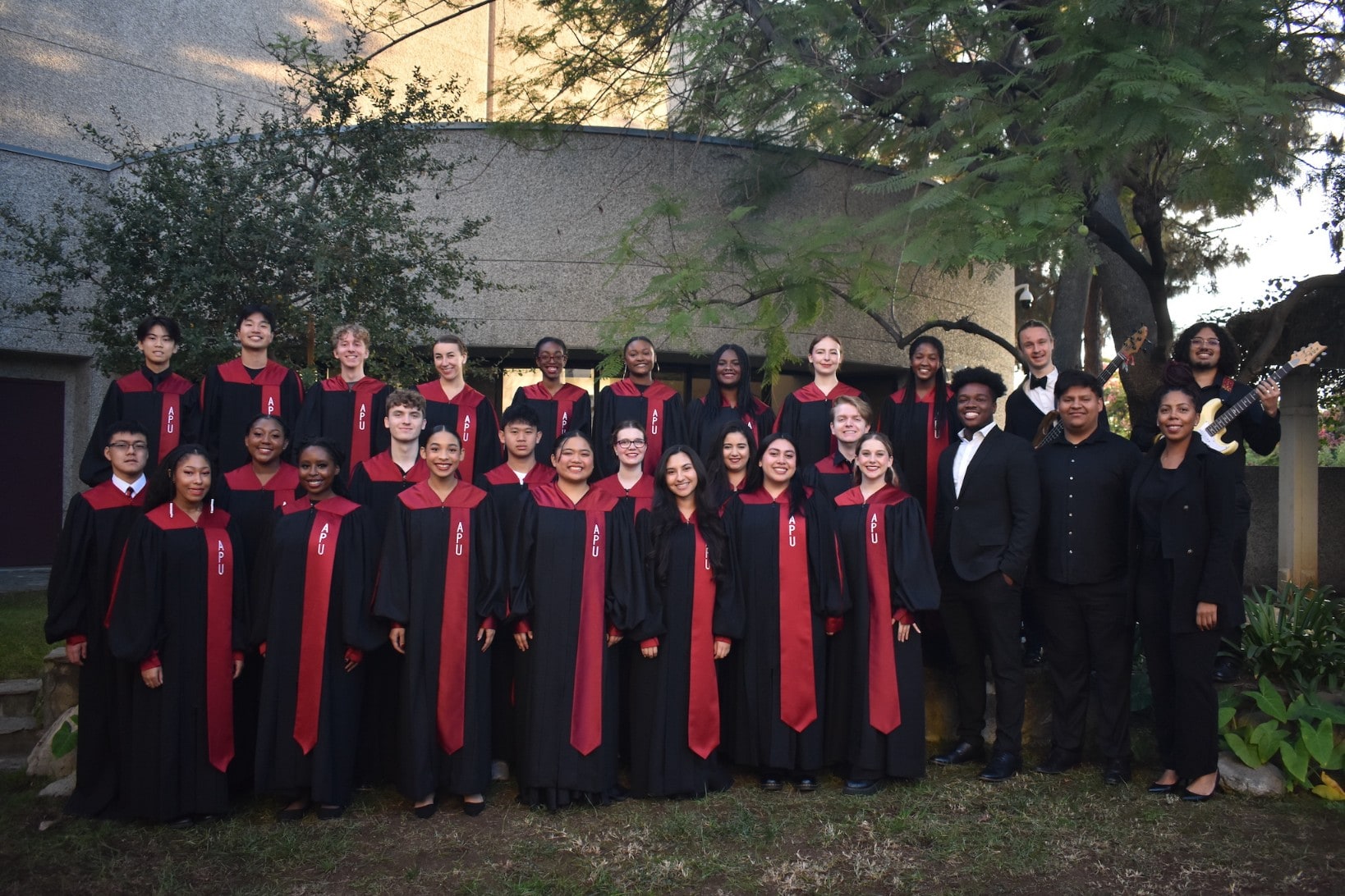 Image of the gospel choir performing in a stage wearing black gown with details in red.