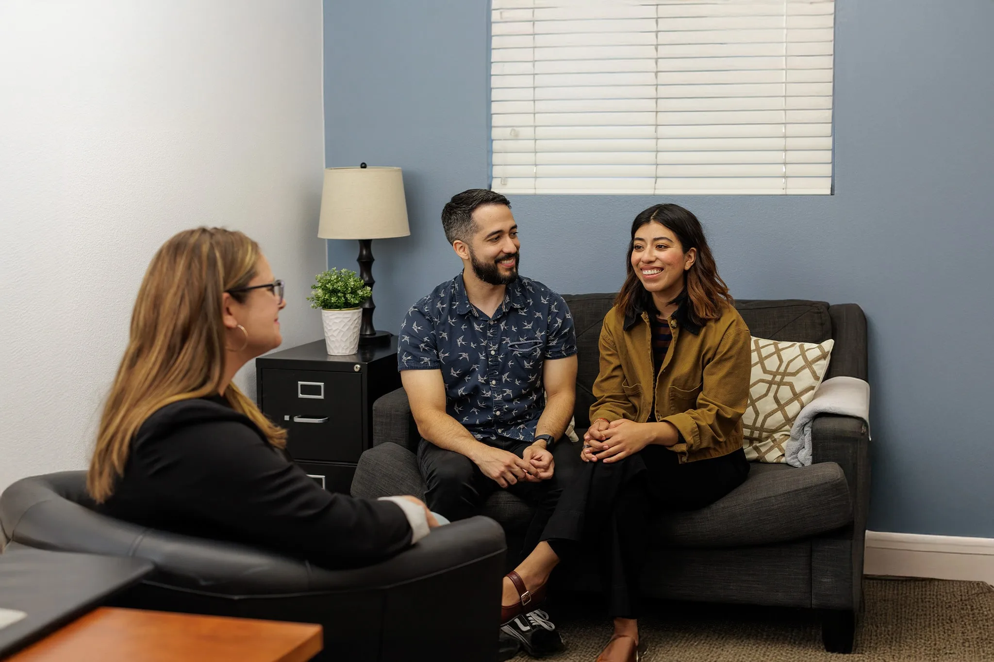 Couple on a couch smiling during therapy session
