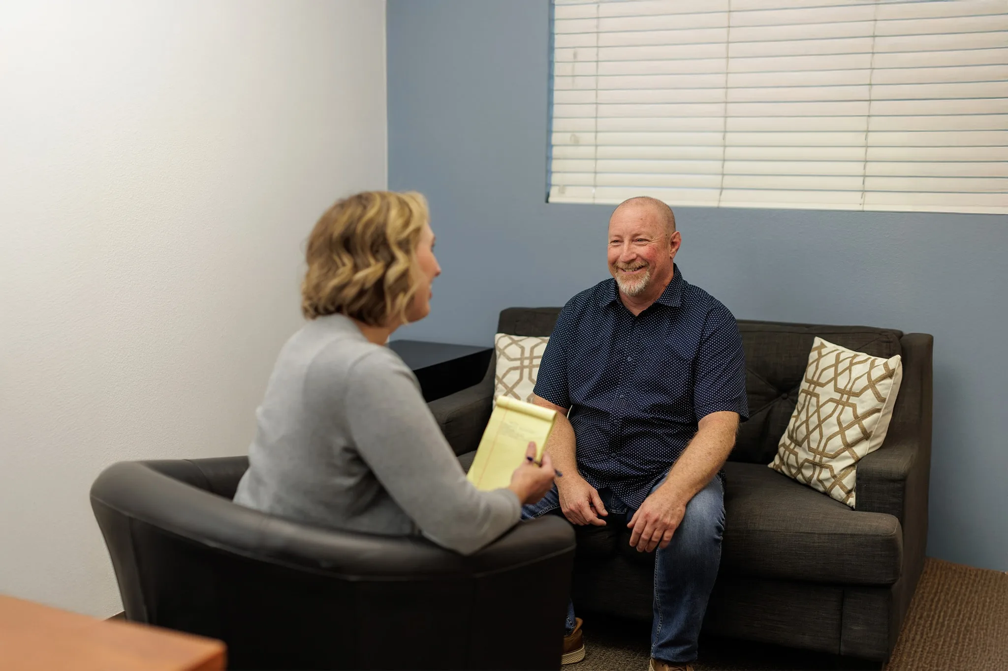 a man  sitting on a couch speaking with counselor