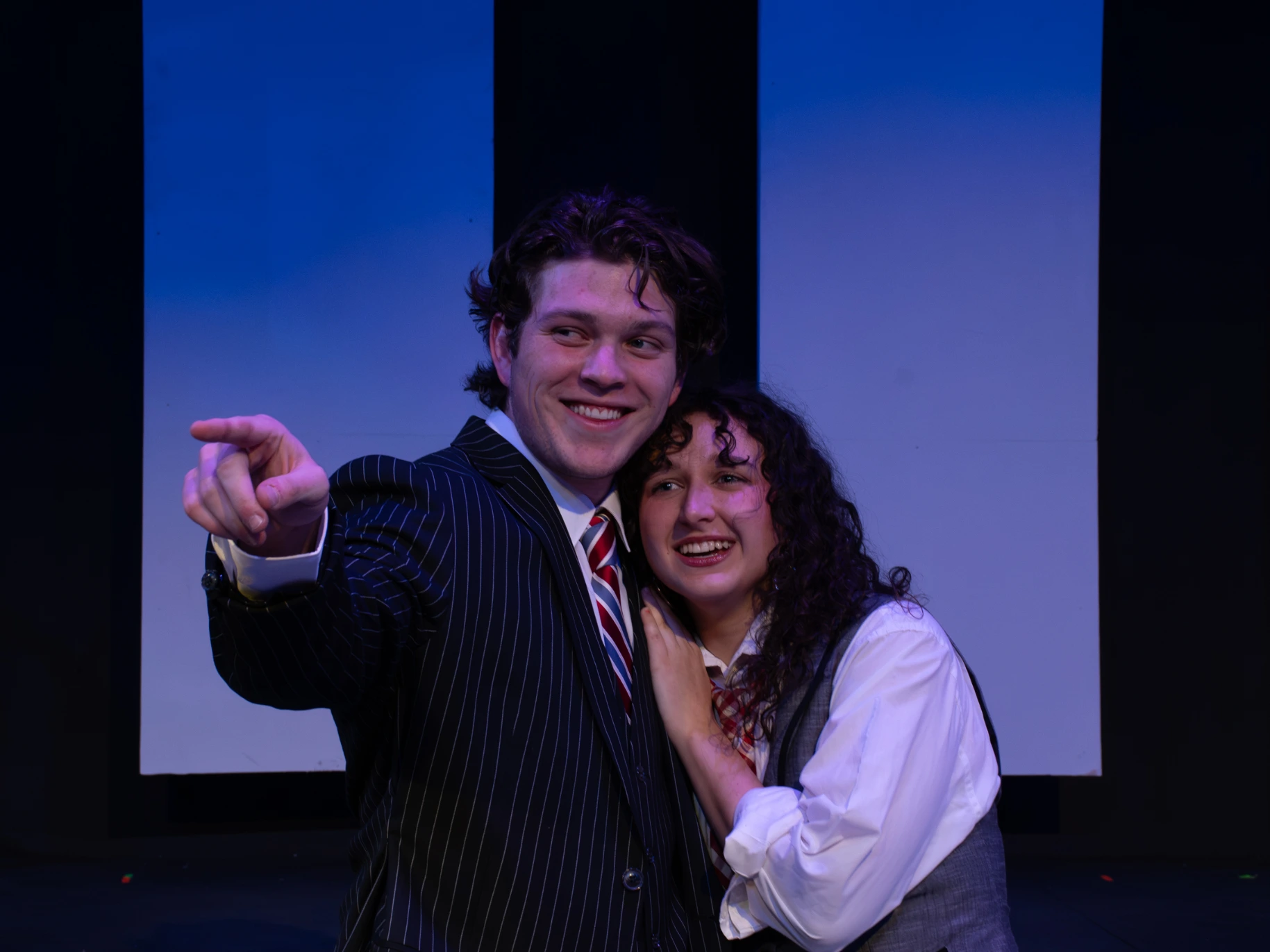 Two actors pose together on stage