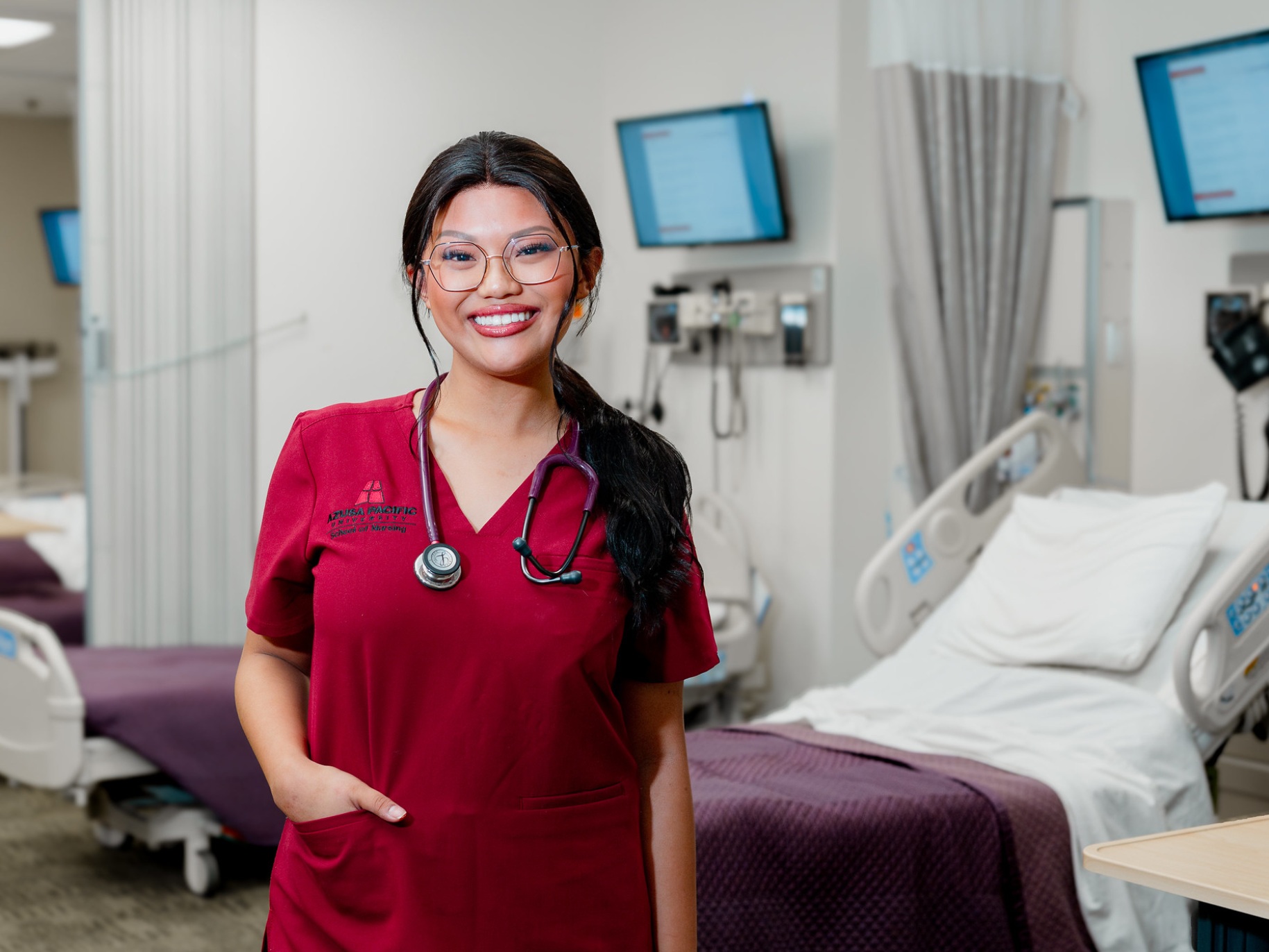 An APU nursing student smiles in a lab classroom
