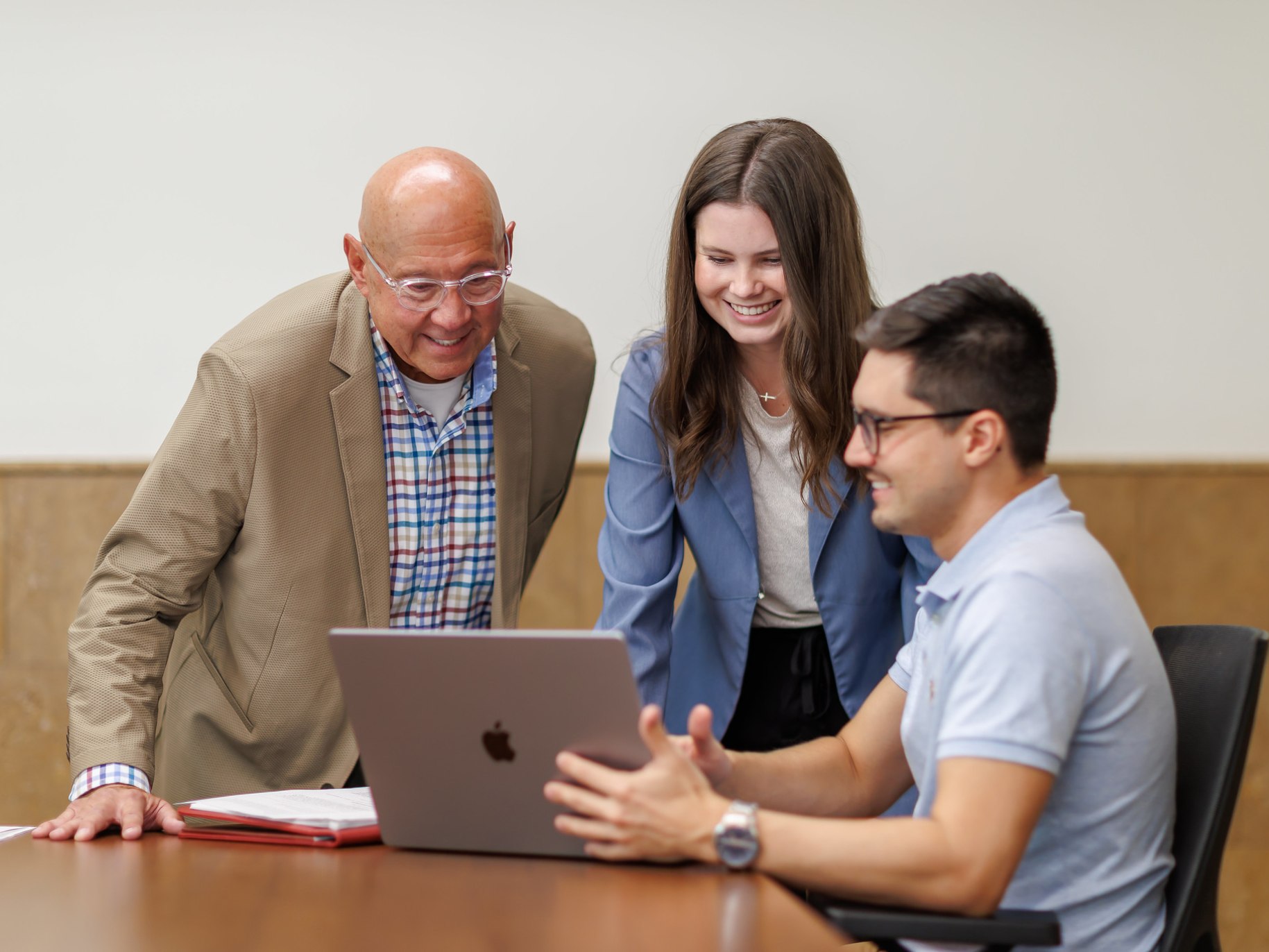 Two students and a professor work on a computer