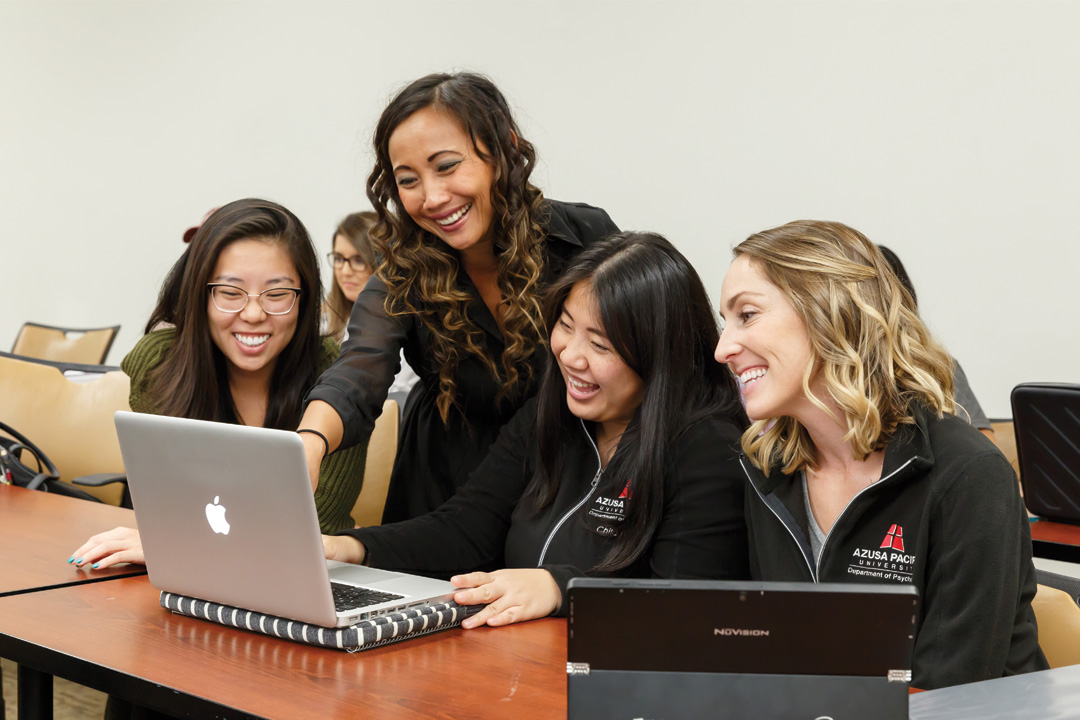 APU counseling psychology program students surrounding a laptop