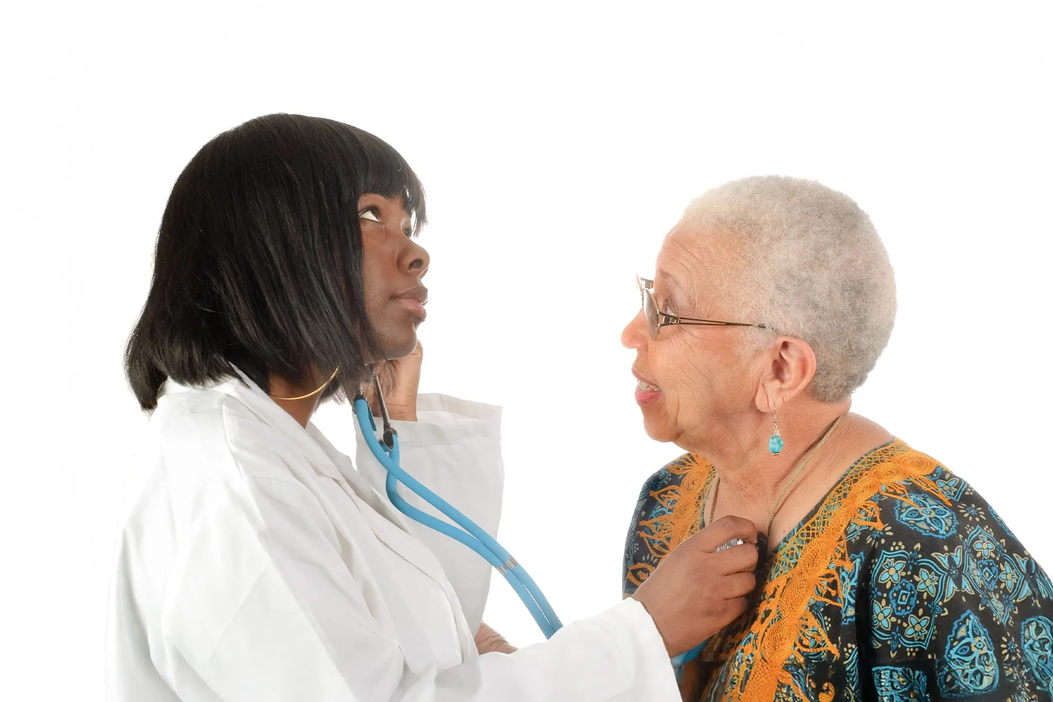 Healthcare provider uses a stethoscope to examine an older adult patient.
